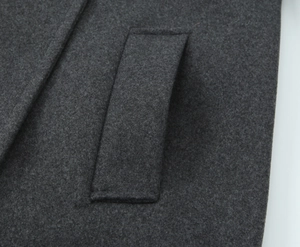 Gros plan sur le détail d'un manteau gris foncé montrant la texture douce et la poche