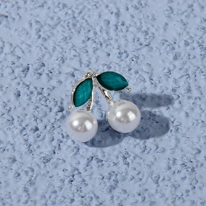 Close-up of cherry earring with white faux pearls and green teardrop enamel leaves