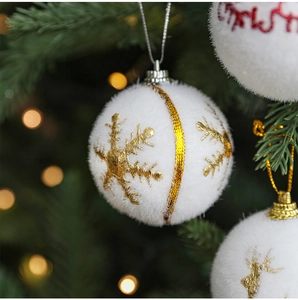 Close-up of white flocked Christmas ball with gold reindeer and snowflake embroidery