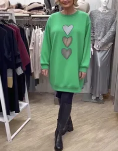 Detalle de vestido sudadera verde de manga larga con tres parches de corazones metálicos