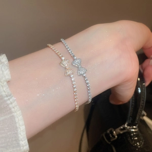 Close-up of sparkling bow pendants on rose gold and silver bracelets on female wrist