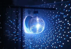 Macro detail of silver mirror disco ball reflecting blue light in a dark ambient setting