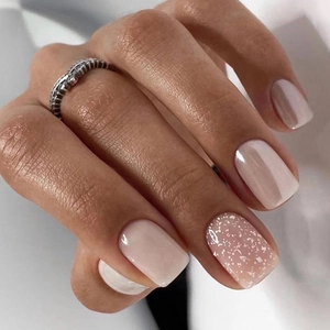 Close-up of pink and cream press-on nails with silver glitter accent and glossy finish