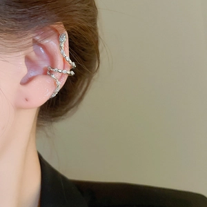 Close-up of curved silver snake ear cuff with sparkling zircon stones on model's ear