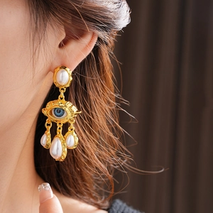 Detail of vintage gold pearl earrings with blue eye motif and cascading teardrop pearls