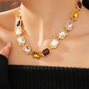 Close-up of vintage gold necklace with multicolored gemstones worn on model neck