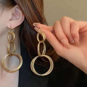 Exaggerated multilayer gold circular drop earrings worn by a model in high quality