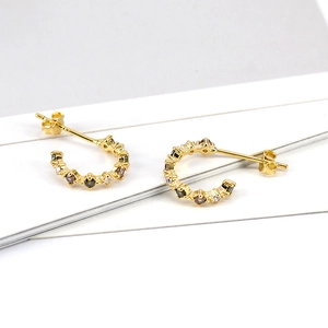 Macro detail of gold C-shaped earrings with colorful zircon stones and secure posts