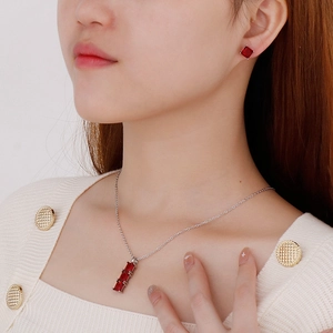 Dettaglio di un set di gioielli con collana e orecchini con pietre rosso rubino su modella