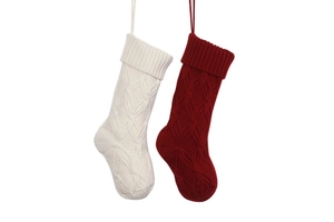 Close-up of red and white cable knit Christmas stockings hanging on a white backdrop