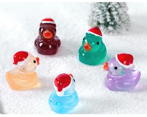Close-up of five colorful Christmas ducks with Santa hats on white artificial snow