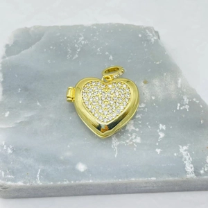 Golden heart-shaped locket pendant with micro-pave cubic zirconia on gray marble background