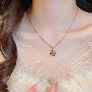 Close-up of gold plated necklace with colorful zircon pendant on model with feather detail