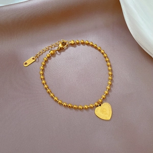 Macro shot of gold bead chain bracelet featuring a heart-shaped Elizabeth II coin pendant