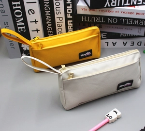 Detailed view of canvas pencil bags in yellow and beige with multi-pocket design