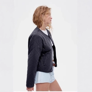 Women's black quilted bomber jacket with a crew neck and zipper closure, minimalist style