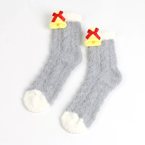 Detail von flauschigen grau-weißen Socken mit gelben Glöckchen und roten Schleifen