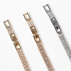Macro detail of gold and silver bracelets featuring rectangular cubic zirconia inlay