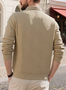 Detail of the back of a khaki knit polo shirt with a textured geometric pattern