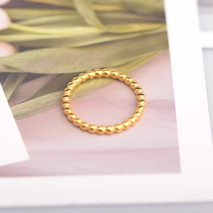 Close-up of a 18K gold beaded wave ring placed on a minimalist botanical background