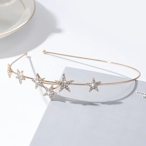 Détail macro du serre-tête en métal doré orné de sept étoiles brillantes en strass