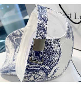Detailed close-up of blue and white floral canvas baseball cap with metal buckle strap
