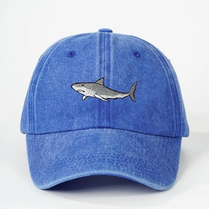 Close-up of the detailed grey shark embroidery on a blue washed denim baseball cap