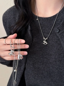Macro shot of silver horse necklace pendant with zircon stones on knit cardigan