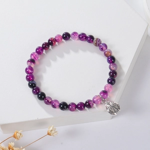 Macro detail of natural purple agate beads with a silver ladybug charm on a display stand
