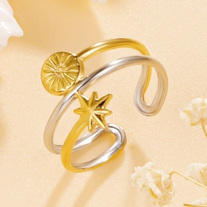 Three-layer stainless steel ring with gold sun and star charms on warm background