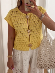 Detailed close-up of yellow crochet cardigan featuring gold sun-shaped buttons and textures