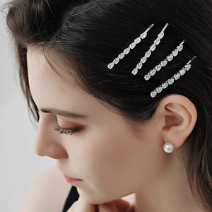 Sparkling rhinestone hair clip set with pearl earrings on a model’s dark hair