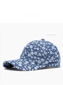 Detail of blue denim baseball cap featuring white floral pattern and premium stitching