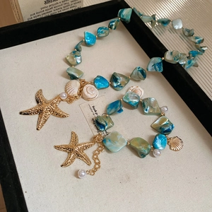 Close-up of beach style blue bead necklace set with starfish, seashell and pearl charms