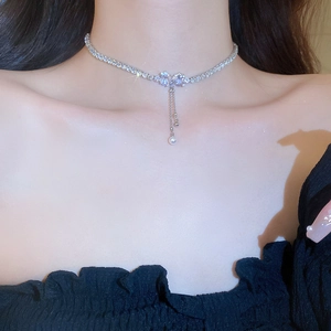 Macro detail of silver-tone bow necklace with sparkling zircon and pearl tassel fringe