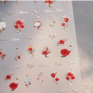 Macro view of 3D embossed nail stickers featuring red roses and gold foil accents