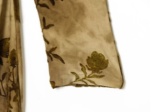 Close-up of olive green velvet flocked pattern and stitching on satin dress cuff