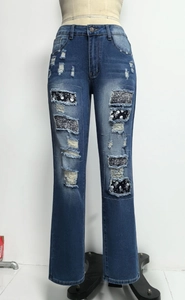 Detail von distressed blauen Jeans mit Pailletten-Totenkopf-Patches und Denim-Struktur