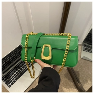 Detailed shot of green leather baguette bag with gold chain and metal buckle