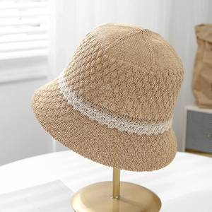 Breathable hollow-out knit straw bucket hat with white lace stripe on metal stand