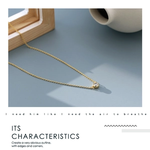 Detail showing gold chain with round zircon pendant against a minimalist backdrop