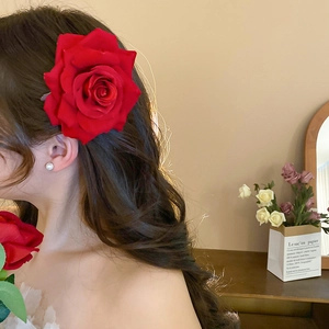 Detail of red fabric rose hair clip and pearl earring on a model in French style
