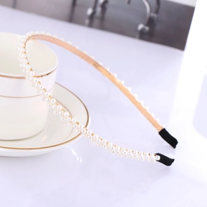 Detail of elegant headband with double-row white pearls on gold metal base and black tips