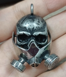 Close-up of vintage punk gas mask skull pendant in antique silver finish held in hand