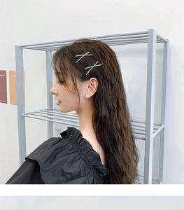 Nahaufnahme minimalistischer X-förmiger Strass-Haarnadeln im Haar einer Frau