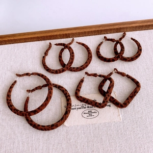 Flat lay of four leopard print fabric earrings in round and square shapes on white fabric