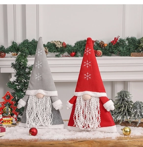 Detailed view of red and grey knitted Swedish gnome dolls on a snowy mantelpiece