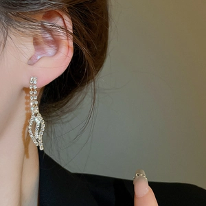 Close-up of elegant leaf-shaped drop earrings with sparkling rhinestones on model