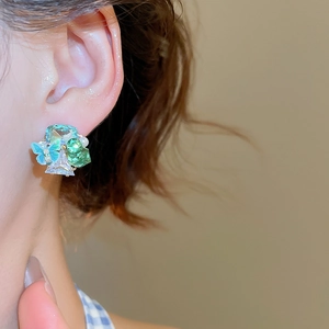 Detail view of cluster stud earring with crystals, pearl and butterfly in 18k gold plating