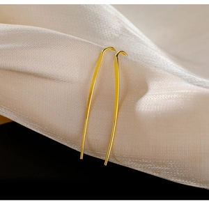 Minimalistische goldene Ohrhänger auf elegantem cremefarbenem Satin-Hintergrund